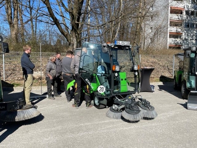 Einige Männer stehen um eine Egholm Kehrmaschine