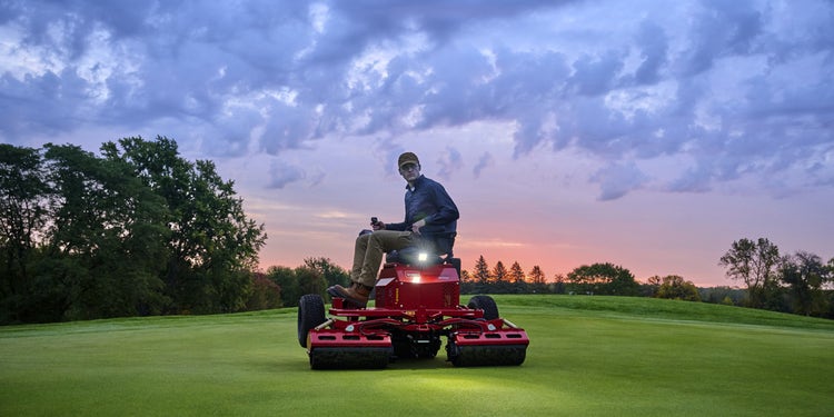Mann sitzt auf Toro GreensPro e1700 in der Abenddämmerung auf einer Grünfläche