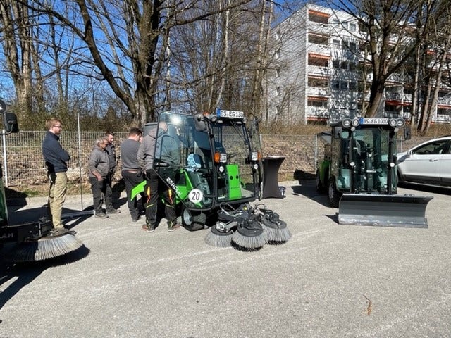 Einige Männer stehen um eine Egholm Kehrmaschine