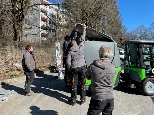 Zwei Männer arbeiten an einer Egholm Kehrmaschinen während zwei andere zusehen