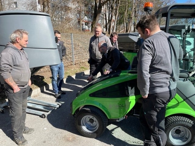 Einige Männer stehen um eine Egholm Kehrmaschine
