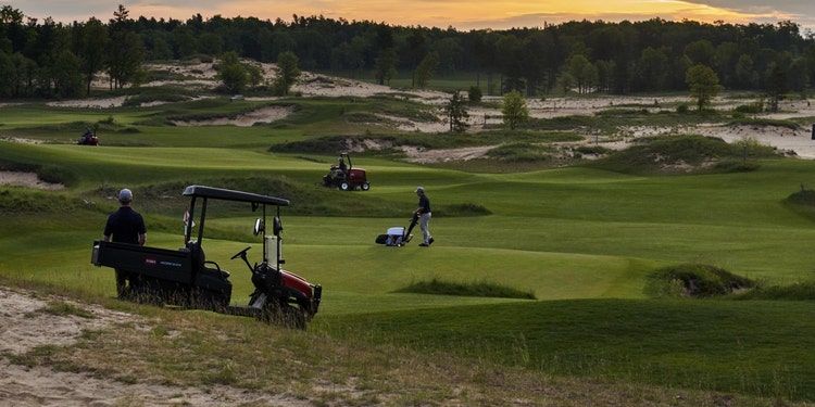 Foto eines Golfplatzes in der Abenddämmerung mit verschiedenen Geräten zur Golfplatzpflege