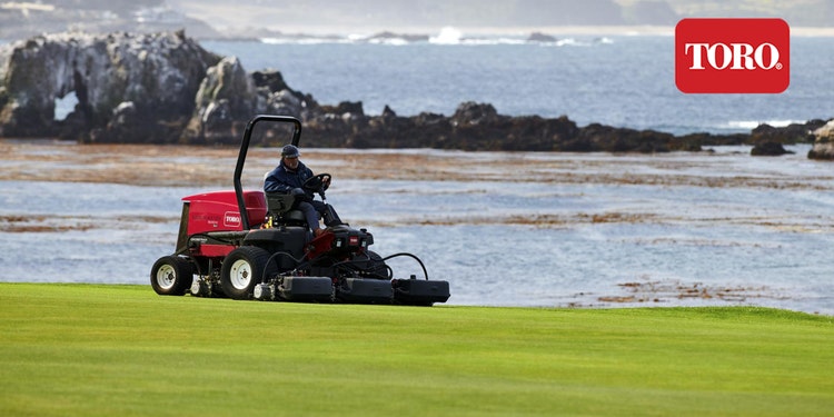 Mann mäht Rasen mit Toro auf Golfplatz