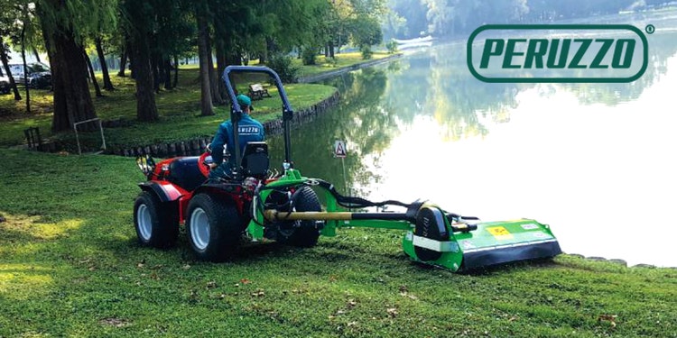 Mann arbeitet mit Peruzzo Anbaugerät auf Grünanlage nahe eines Sees