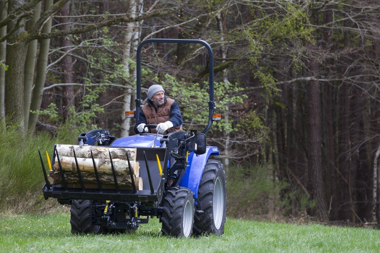 Mann sitzt auf Iseki TLE 3410 AL Traktor und transportiert Ware in der Schaufel