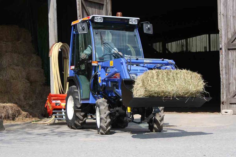 Iseki TM 3207 AL Traktor hat einen Heuballen auf der Schaufel