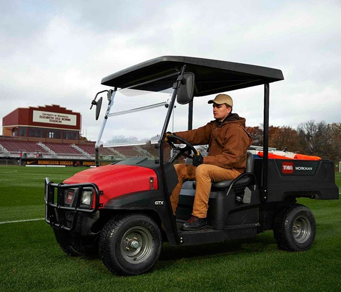 Mann fährt Toro Workman GTX auf Sportplatz
