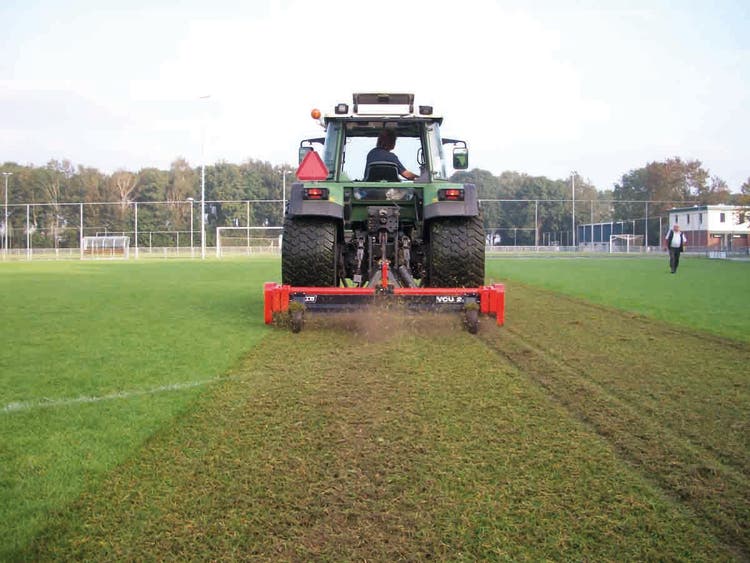 Traktor fährt über Sportplatz mit Trilo VCU Vertikutierer
