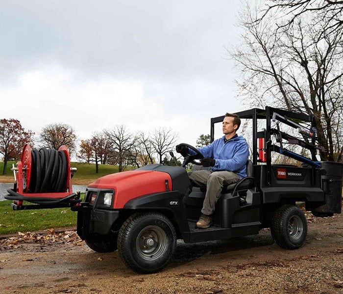 Mann fährt auf Toro Workman GTX mit Aufbau an Ladefläche