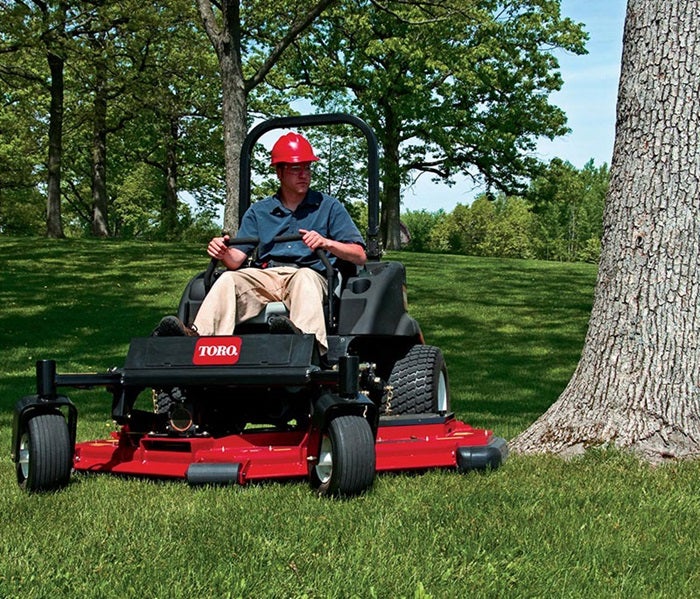 Mann mäht mit Toro GroundsMaster 7210 um einen Baum